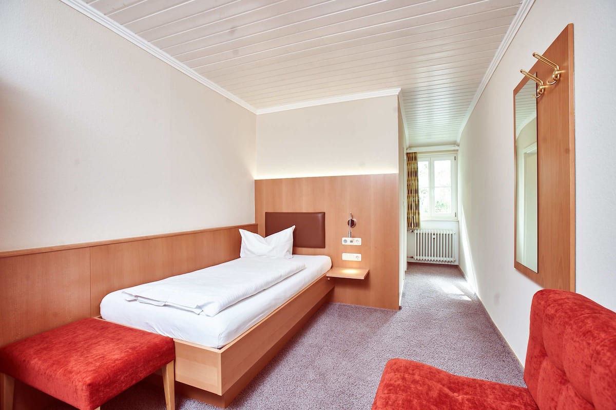 Un dormitorio con una cama de madera, un banco, una mesita de noche y un espejo.