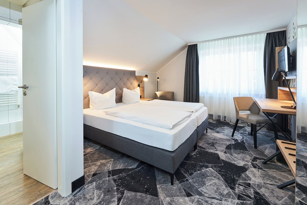 Una habitación de hotel moderna con una cama grande, un escritorio y una televisión.