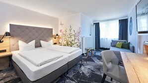 A modern hotel room with a large bed, a desk, and a sofa. - Das Landhotel Am Trätzhof (Fulda)