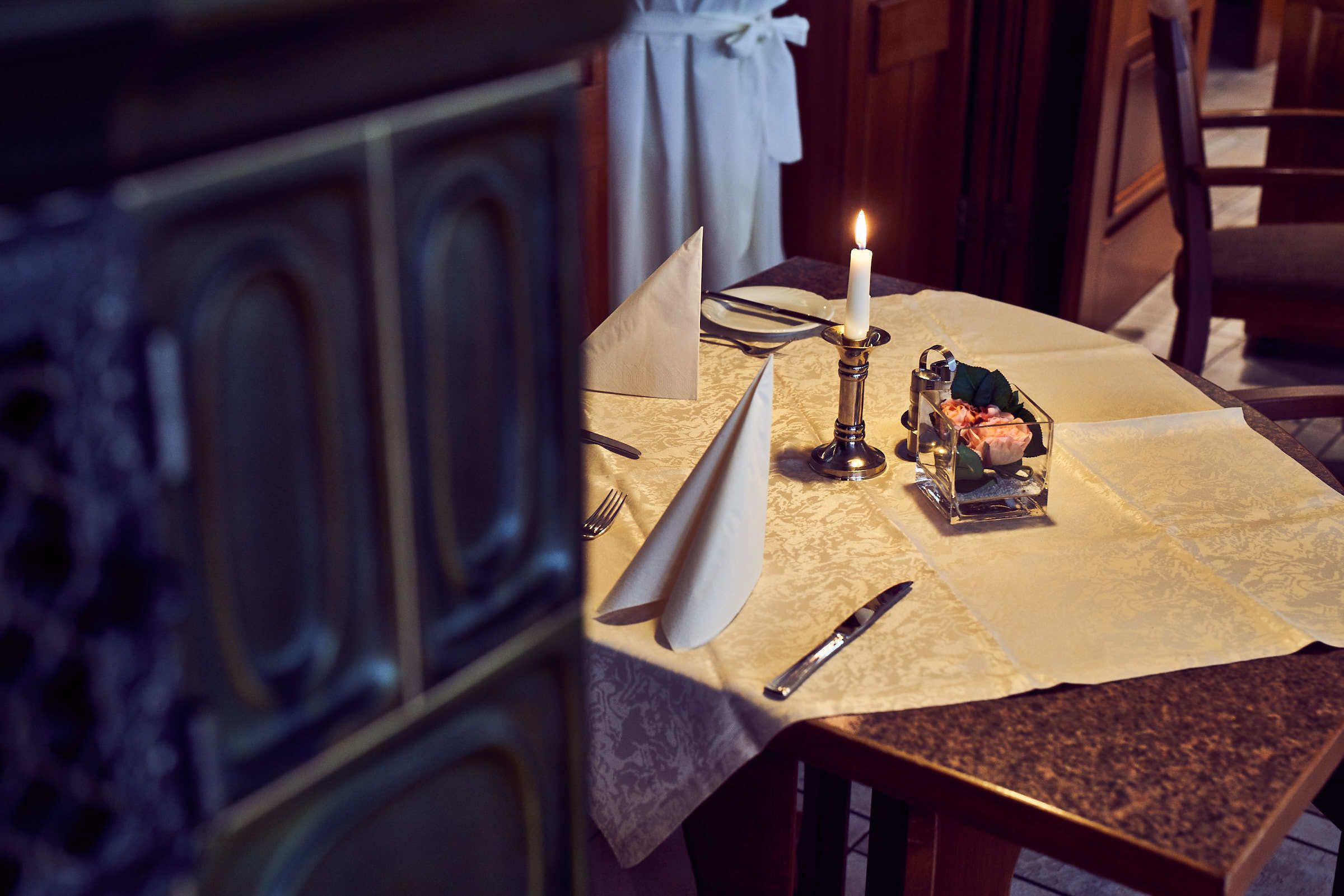 A dining table set with a candle, a salt and pepper shaker, a napkin, a knife, and a folded napkin.