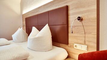 Een hotelkamer met een houten hoofdbord, witte beddengoed en een rode stoel.