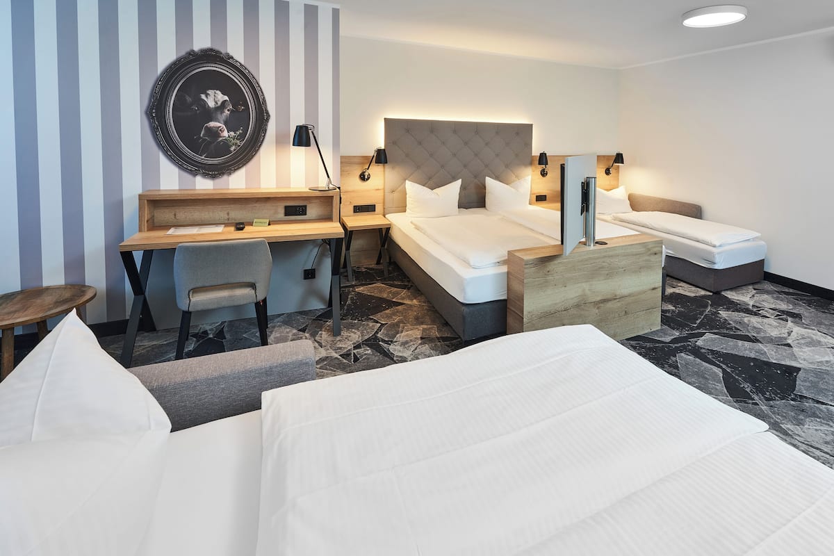 Una habitación de hotel con cama, escritorio, silla y mesita de noche.