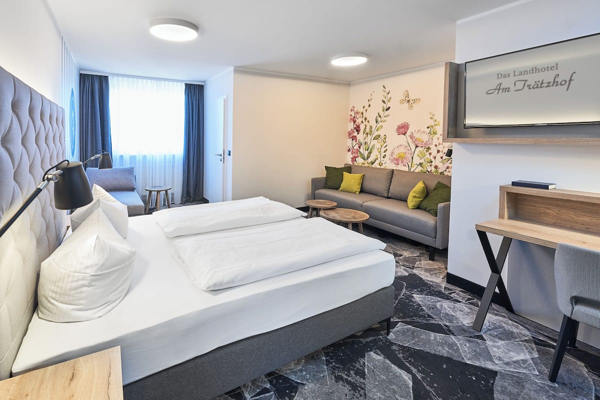 Una habitación de hotel con una cama, un sofá, una mesita y un escritorio.