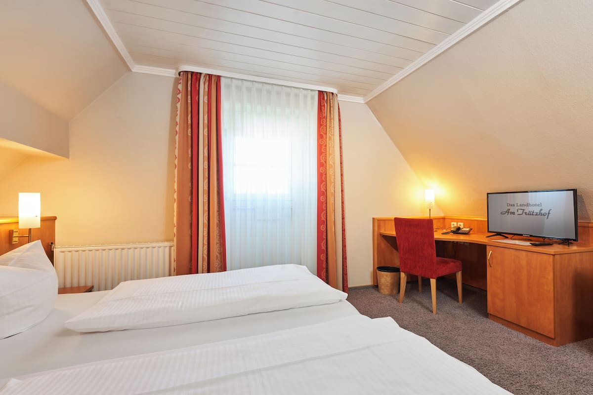 Una habitación de hotel con una cama, un escritorio, un televisor y una silla roja.