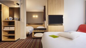 A hotel room with a large bed, a wooden wardrobe, a flat-screen TV, and a red chair.