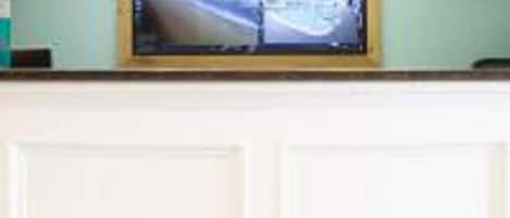 A reception desk with a television mounted above it displaying a scenic view.