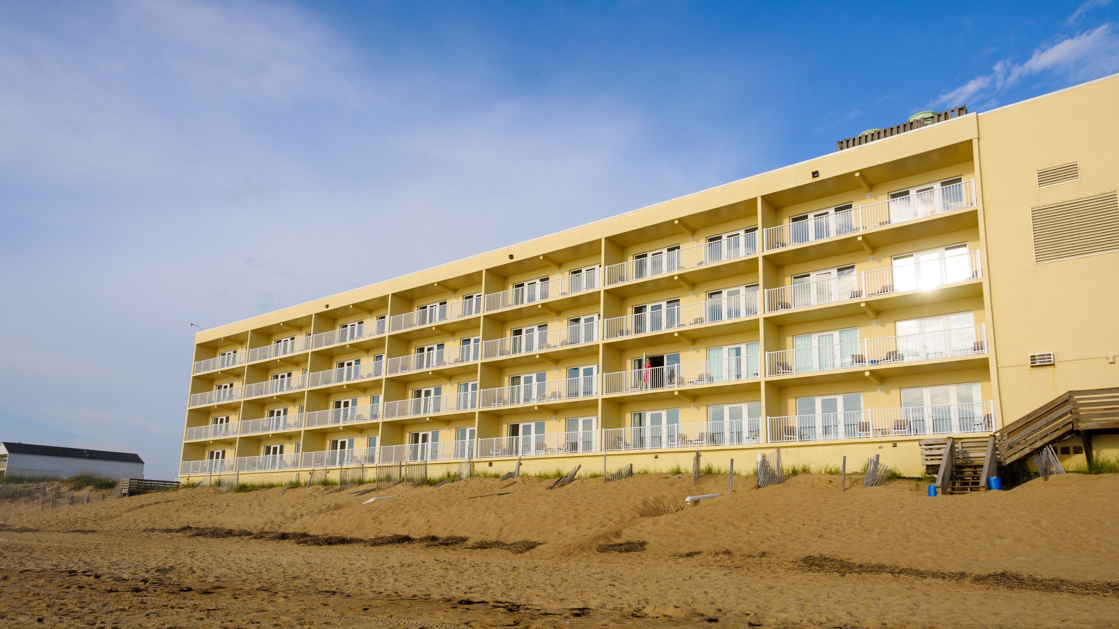 Ein mehrstöckiges Hotel mit Balkonen direkt am Sandstrand.