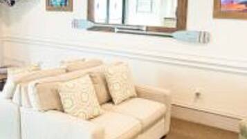 A beige sofa with patterned cushions in a room with a large mirror above it.