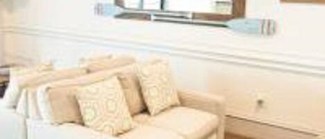 A beige sofa with patterned cushions in a room with a large mirror above it.