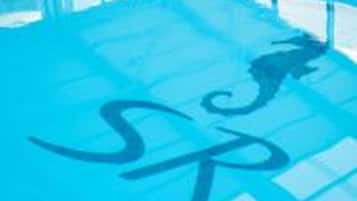 Una piscina con superficie de agua azul cristalina y un logo en el suelo.