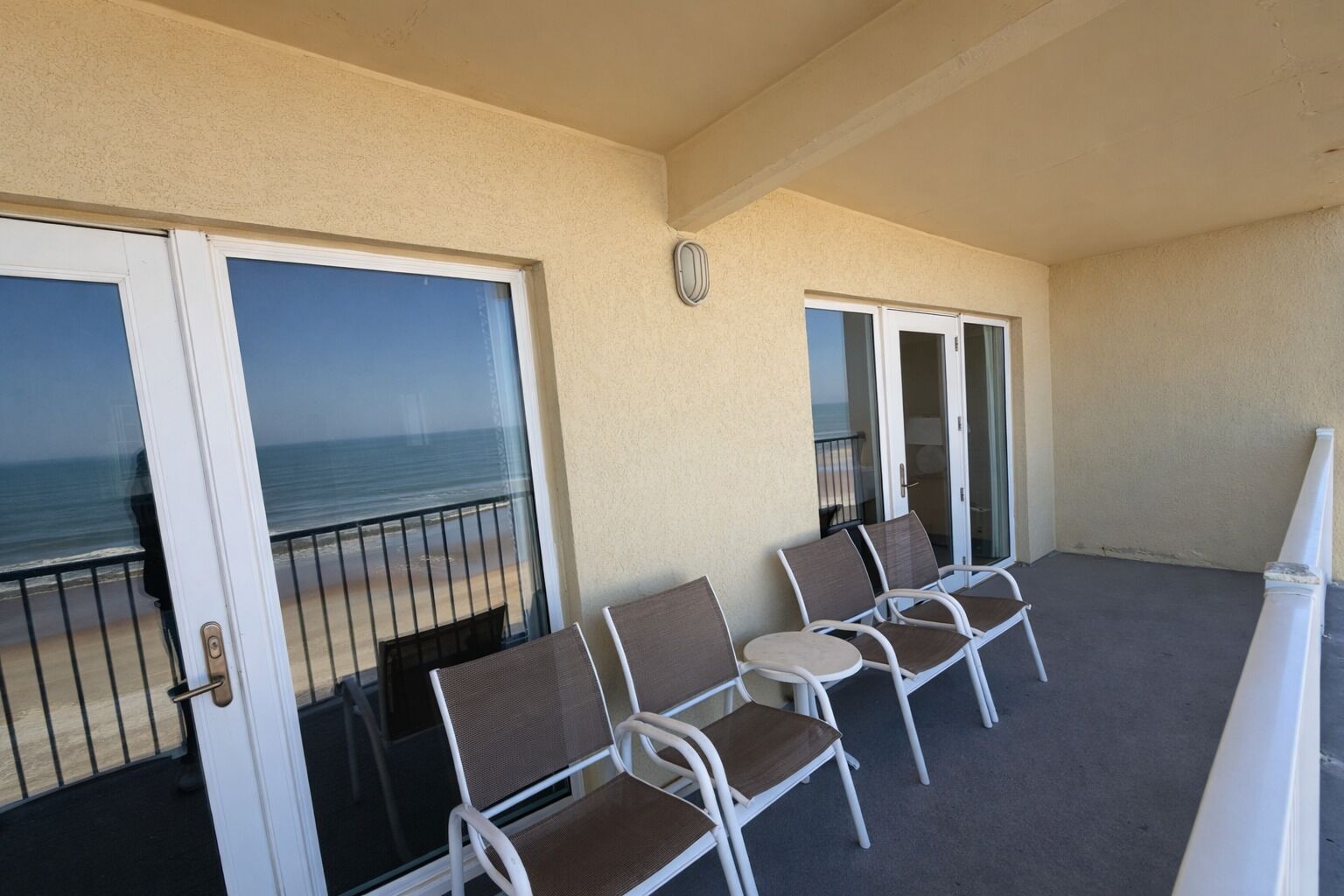 Un balcon avec des chaises, une horloge et une vue sur l’océan.