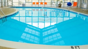 Una piscina interna con soffitto alto e ampie finestre.