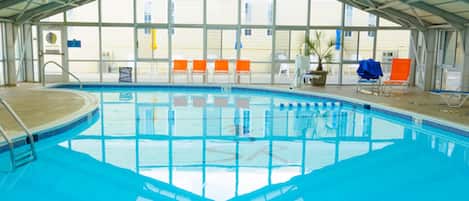 An indoor swimming pool with a high ceiling and large windows.
