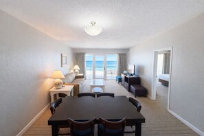 A hotel room with a dining area, a sofa, a TV, and a balcony with a view. - Sea Ranch Resort (Kill Devil Hills)