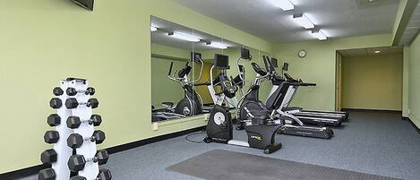 Un gimnasio con equipo de ejercicio, un espejo y un reloj en la pared.