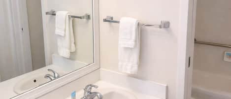A bathroom with a sink, mirror, towel rack, and a toilet.