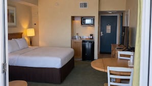 Camera d'albergo con un letto, una scrivania, una sedia, un forno a microonde e un angolo cottura.