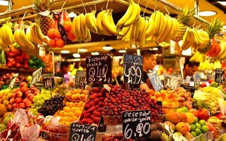 A fruit stand with various fruits and prices displayed.