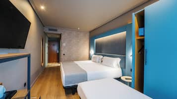 A hotel room with two beds, a desk, and a TV.
