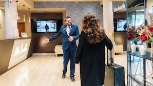Et hotellets reception område med et moderne design, en receptionsdisk og et tv, der viser en person.