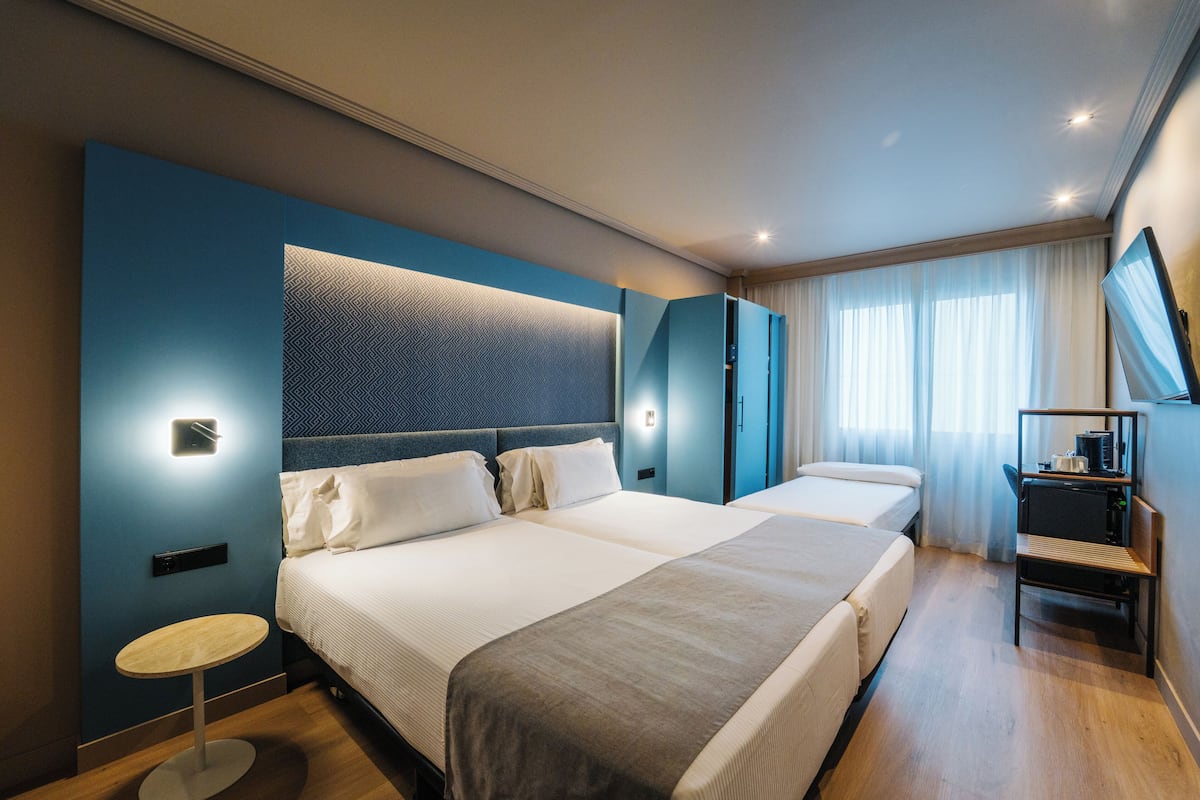 Et moderne hotelværelse med en stor seng, et lille rundt bord og et fjernsyn på væggen.