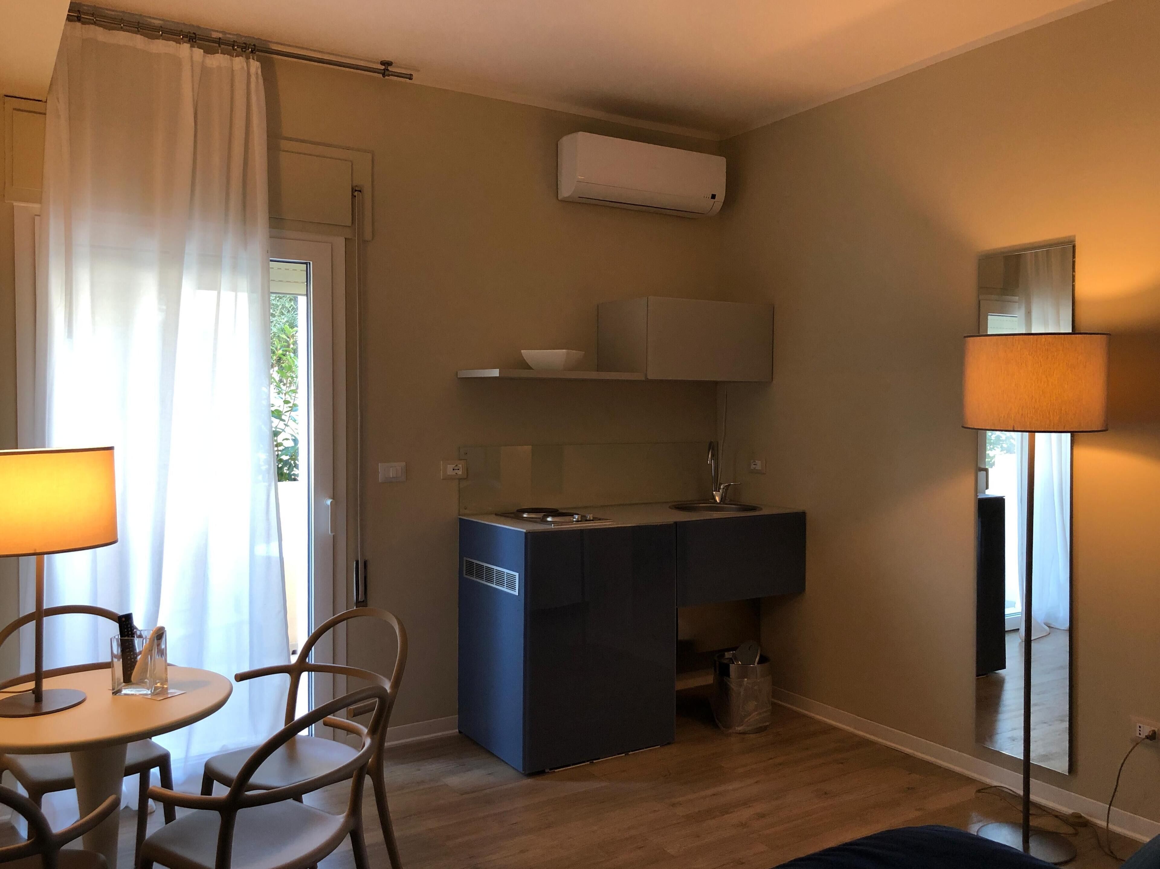 Una cocina compacta con un lavabo, una pequeña encimera y una ventana con cortinas.