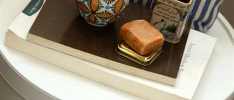 Un bote de basura blanco con un libro, una taza estampada y un pequeño recipiente encima.