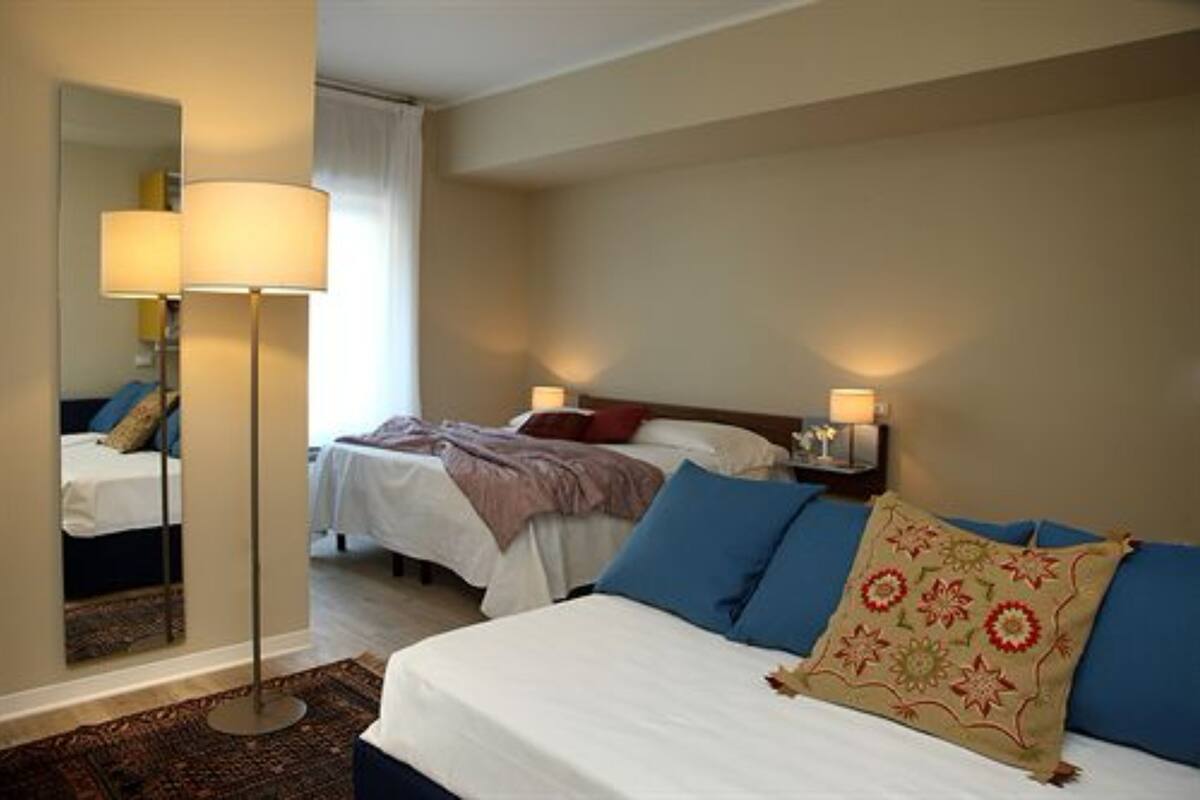 Habitación de hotel con dos camas, un espejo grande y lámparas de noche.