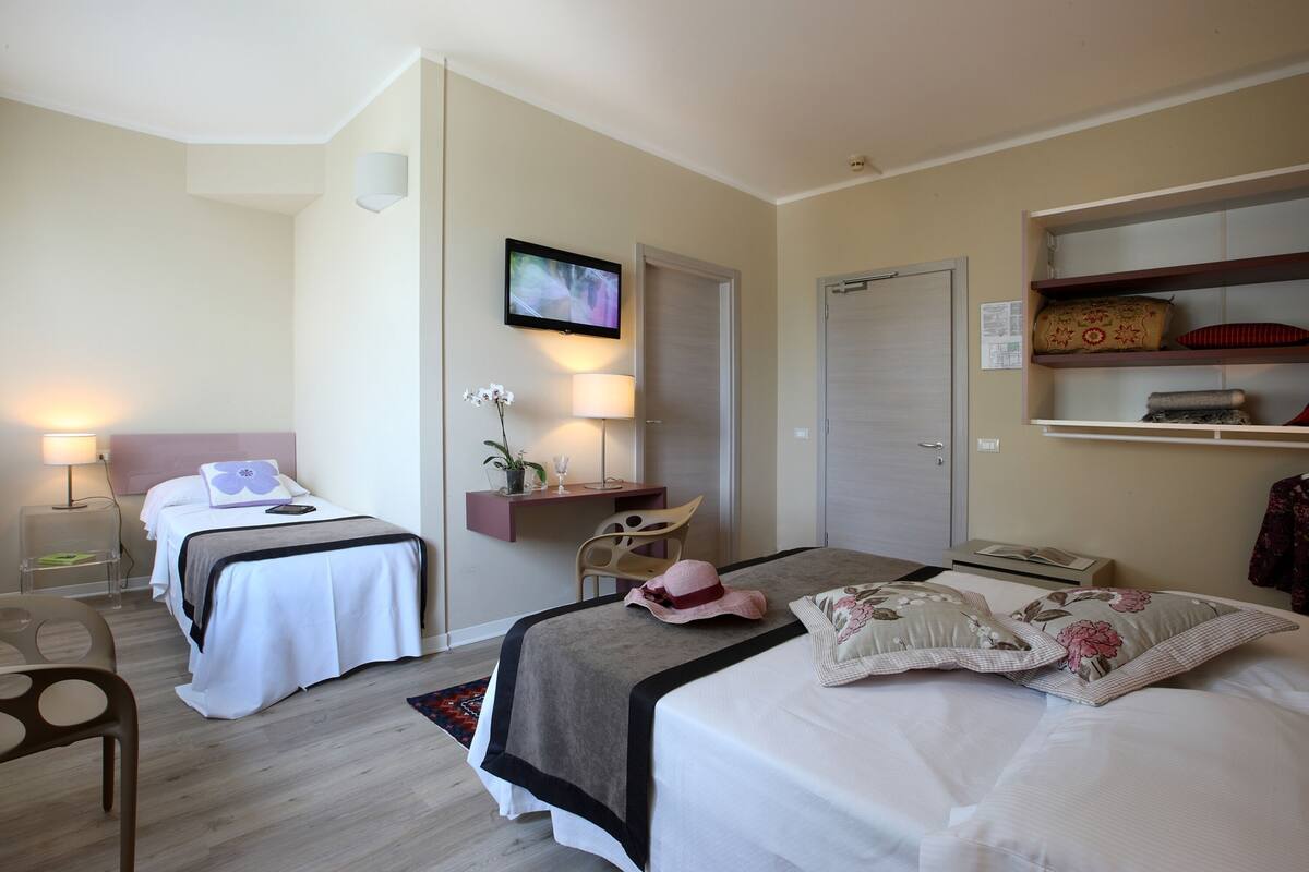 Una habitación de hotel con dos camas, un escritorio, un televisor y un armario.