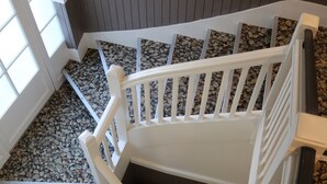 Una escalera con barandillas blancas y suelo de losas de piedra.