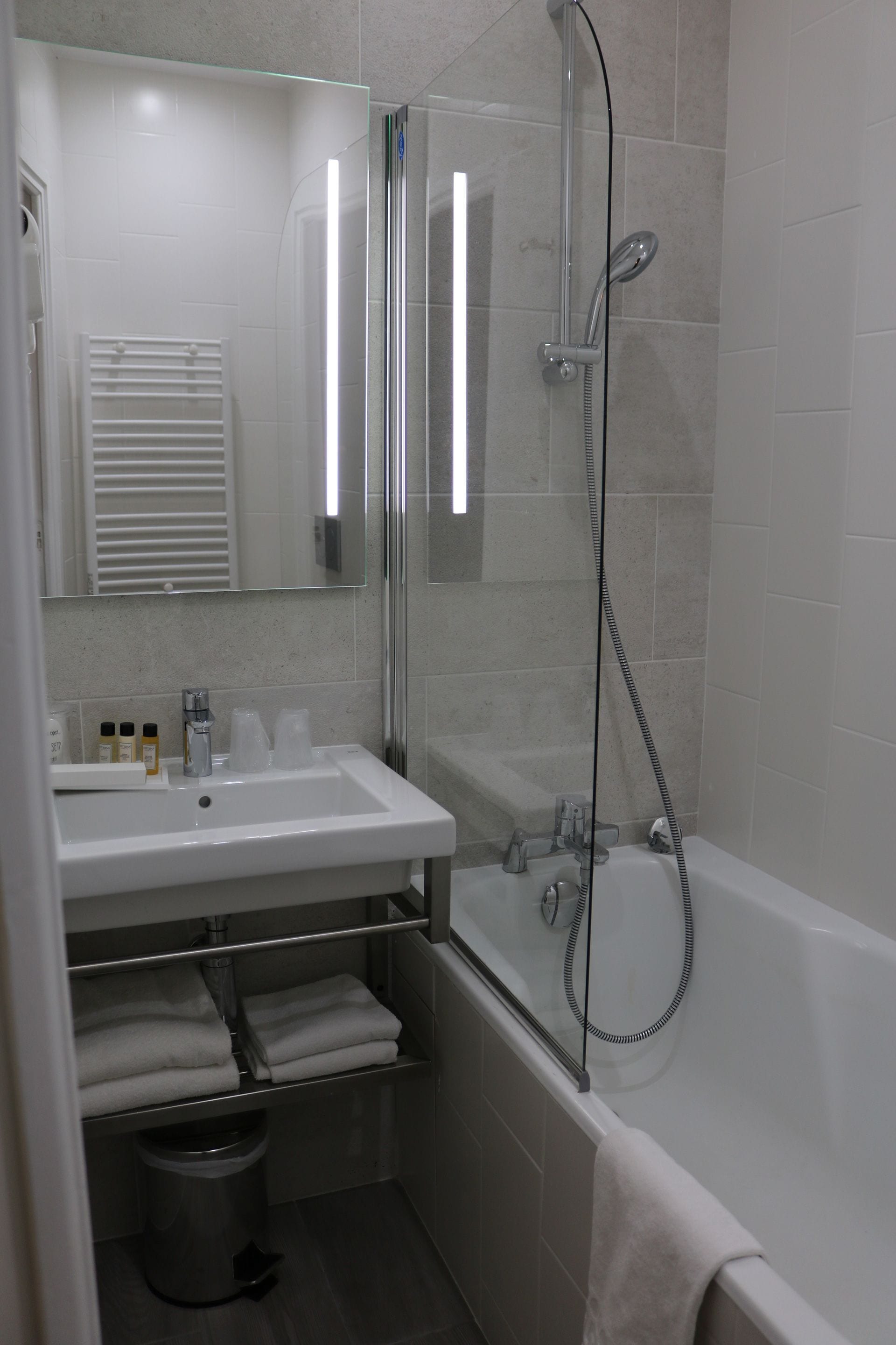 Une salle de bain moderne avec une douche à parois de verre, un lavabo blanc avec un miroir au-dessus, et une baignoire.