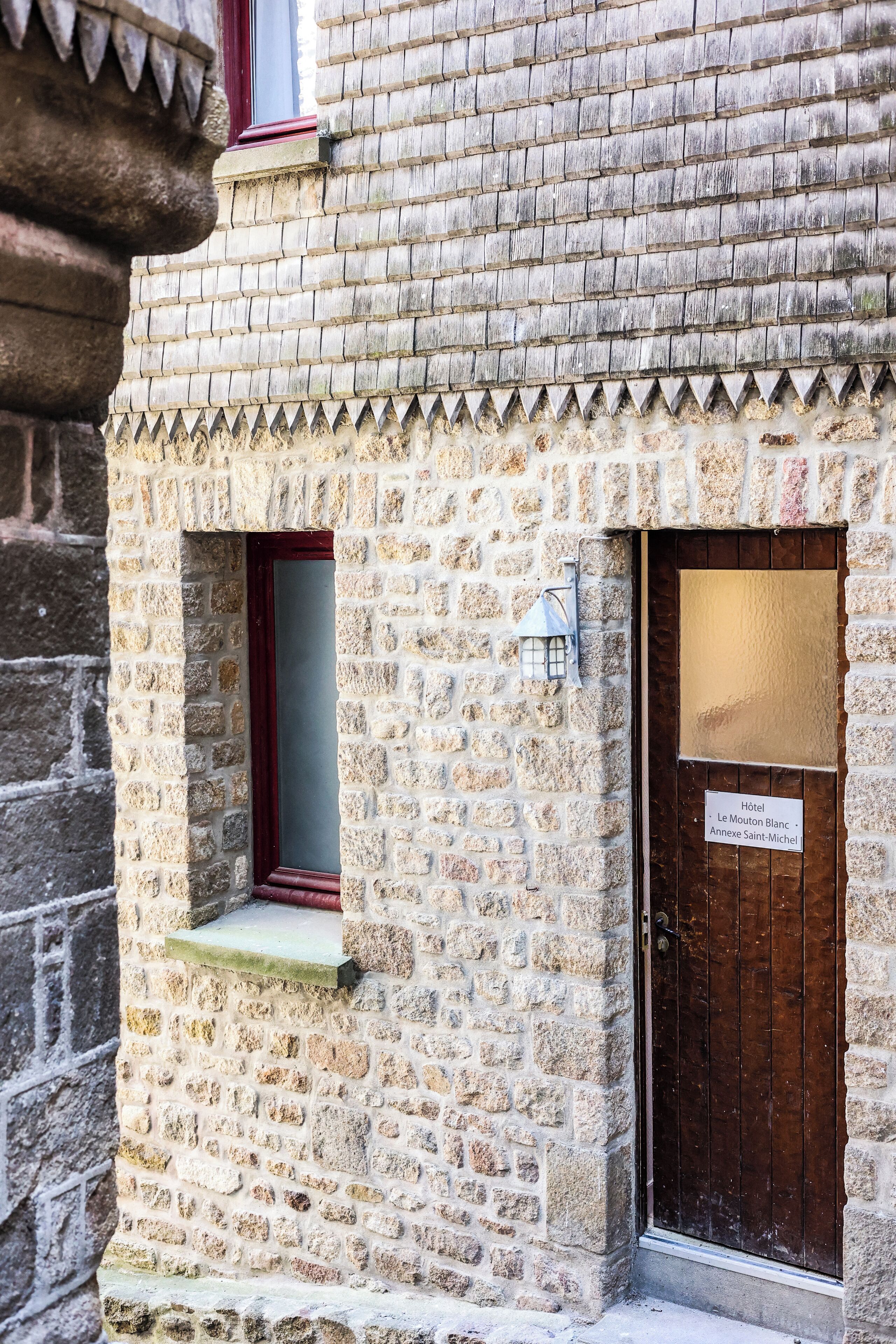 Un bâtiment en pierre avec une porte en bois et une petite fenêtre.