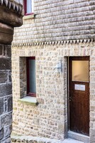 Un edificio de piedra con una puerta de madera y una ventana pequeña.