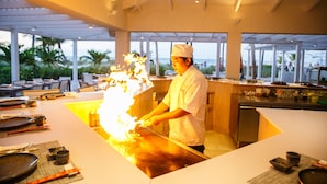 A chef preparing food at a counter in a well-lit kitchen with a view of the outdoors. - Ocean Club West, Grace Bay Beach (Providenciales)