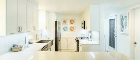 A modern kitchen with white cabinetry, a central island, and artwork on the walls.