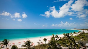 A beach with white sand, turquoise water, and palm trees. - Ocean Club West, Grace Bay Beach (Providenciales)