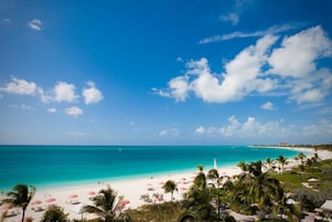 A beach with white sand, turquoise water, and palm trees.