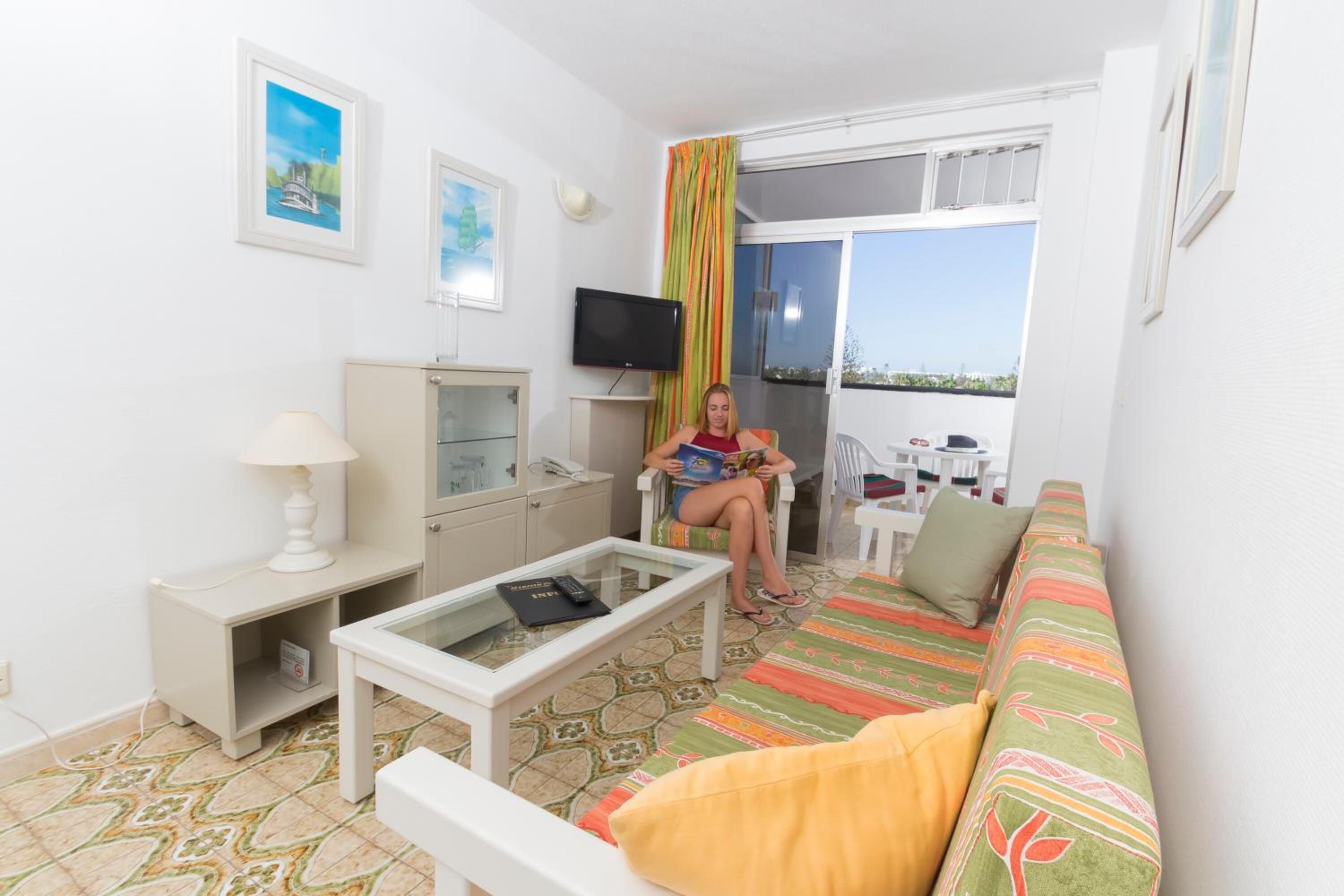 A bright living room with a sofa, a coffee table, and a TV.