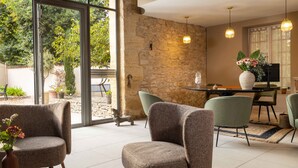 A modern interior with a stone wall, large windows, and a dining area with chairs and a table.