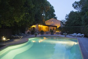 Una piscina con lettini e un edificio con posti a sedere all'aperto.