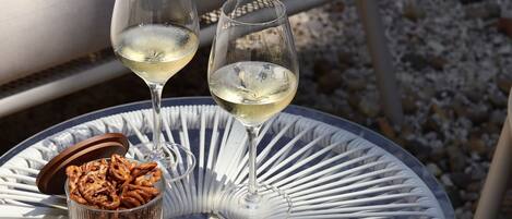 A round glass table with two wine glasses and a bowl of snacks.