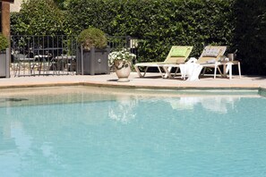 Relax by the serene pool surrounded by lush greenery and comfortable lounge chairs.