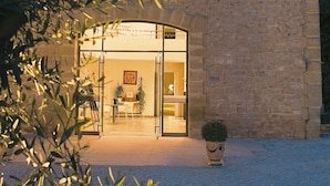 A stone building with a large glass entrance, a small circular window, and a potted plant in front.