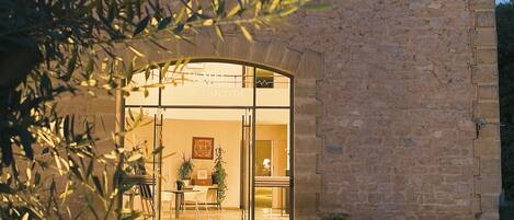 A stone building with a large glass entrance, a small circular window, and a potted plant in front.
