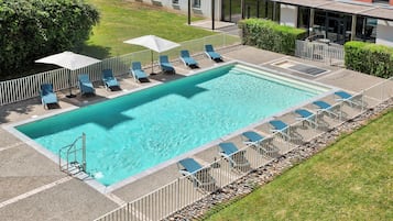 Een buitenzwembad, ligstoelen bij het zwembad