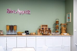 Una encimera de cocina con frascos de condimentos, una cafetera y un letrero que dice 'Bon Appetit'.