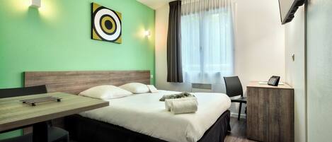 Une chambre d’hôtel avec un lit, un bureau, une chaise, une télévision et une fenêtre avec des rideaux.
