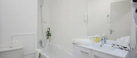 A modern bathroom with a bathtub, toilet, sink, and a large mirror.
