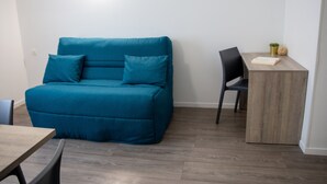 A room with a teal sofa, a wooden table, and a chair. - Comfort Aparthotel Toulouse Metropole (Toulouse)