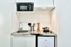 Eine kleine Küche mit einer Mikrowelle, einem Spülbecken und einem Kühlschrank.
